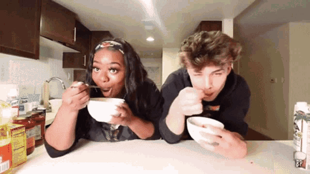 a man and a woman are sitting at a table eating bowls of food