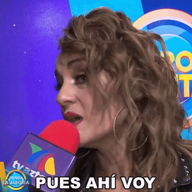 a woman speaking into a microphone with the words " pues ahi voy " written below her