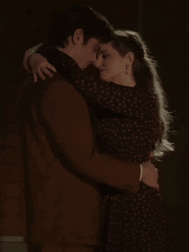 a man in a suit and a woman in a polka dot dress are hugging each other