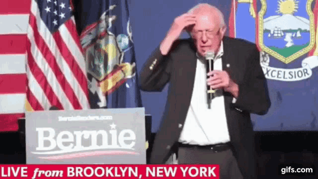 a man stands in front of a sign that says bernie on it
