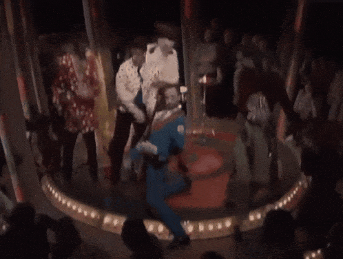 a group of people are dancing on a stage in front of a crowd .