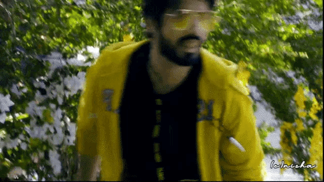 a man wearing sunglasses and a yellow jacket is standing in a forest
