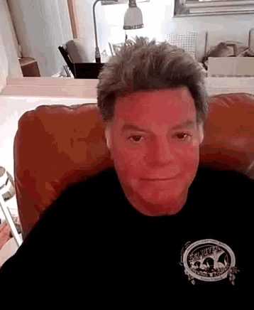a man with red spots on his face is wearing a black shirt with a skull on it