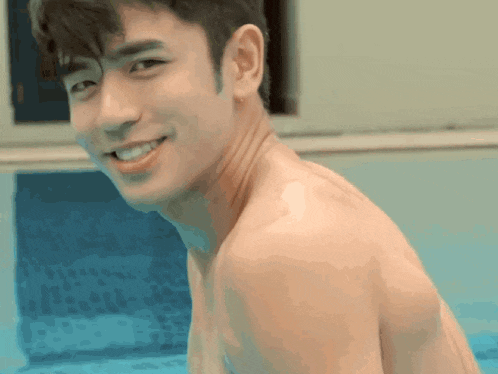 a shirtless man is smiling and looking over his shoulder