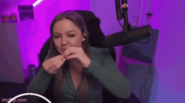 a woman is sitting in a chair in front of a microphone eating a piece of pizza .