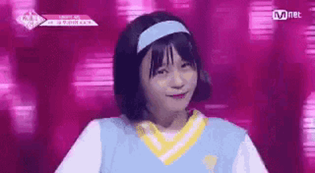 a girl with short hair is wearing a blue headband and a blue sweater .