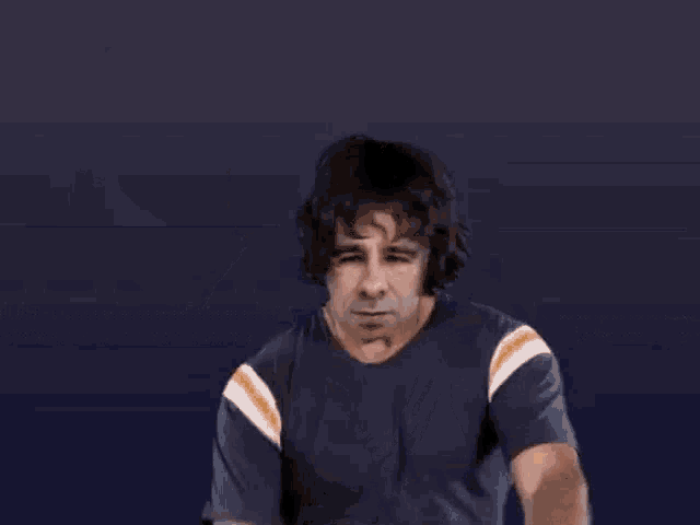 a man in a blue shirt is making a funny face and giving the middle finger .