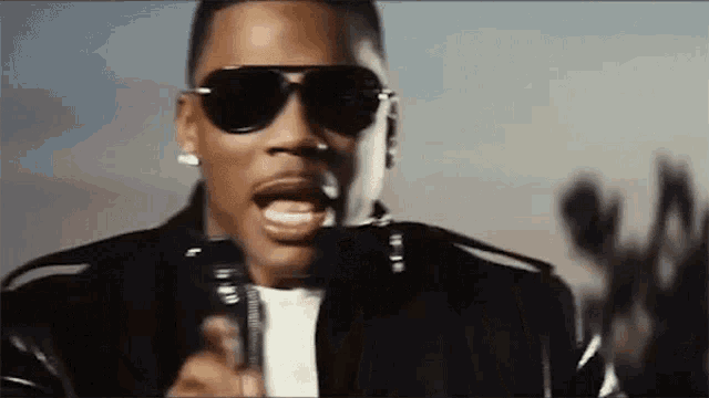 a man wearing sunglasses is holding a microphone