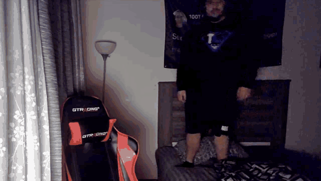 a man is standing in front of a gtr racing chair