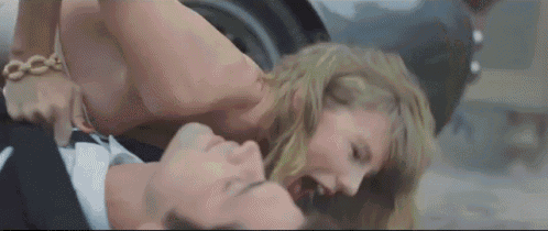 a naked woman is laying on top of a man in a suit .