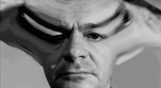 a black and white photo of a man 's face with a strange expression on his face .