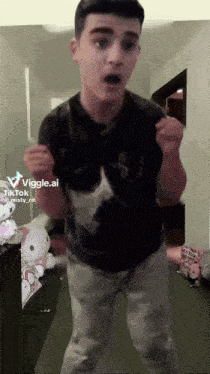 a young man in a black shirt is dancing in a room with stuffed animals behind him