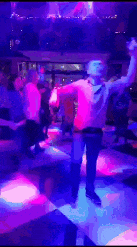 a man is dancing on a dance floor with purple and blue lights