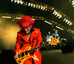a man in a red suit is playing a yellow and orange guitar