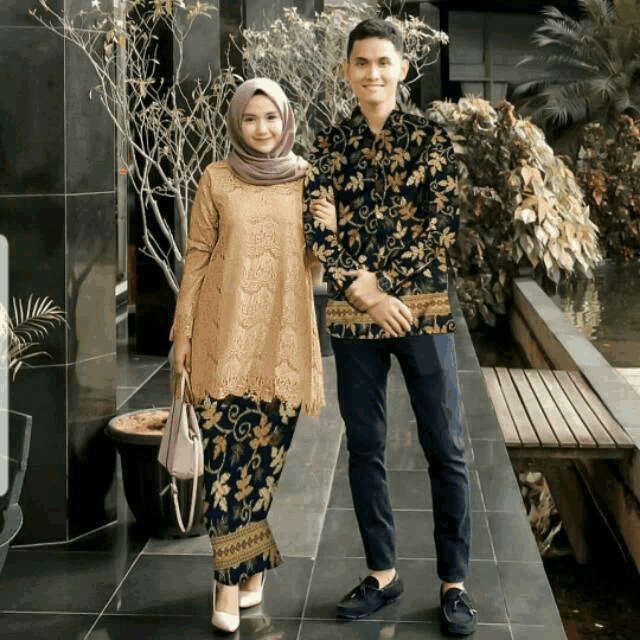 a man and a woman standing next to each other in front of a building