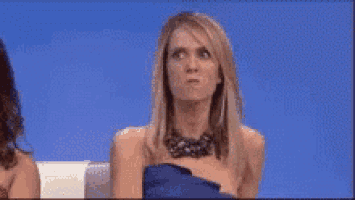 a woman in a blue dress is sitting on a couch with a blue background .
