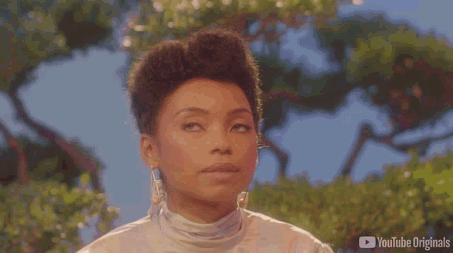 a woman wearing earrings and a white turtleneck is looking up at the sky ..