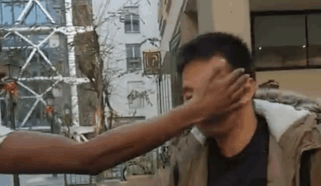 a man 's face is being touched by another man 's hand .
