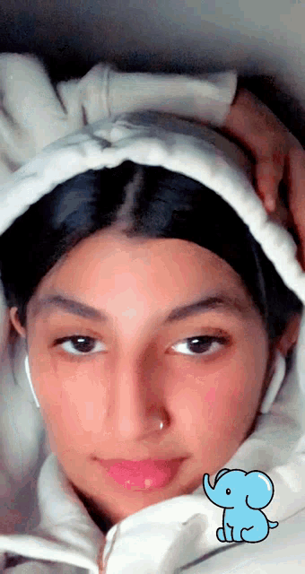 a girl wearing a white jacket has a blue elephant sticker on her face