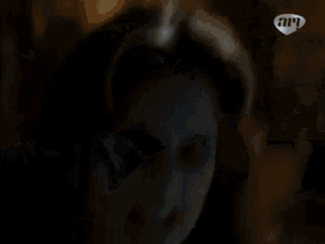 a woman is putting pillows on a bed in a dark room with a sign that says ' a ' on it .