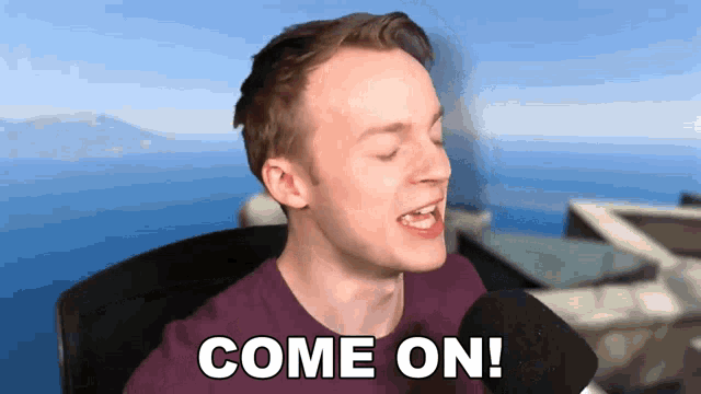a man in a purple shirt says come on in front of a microphone