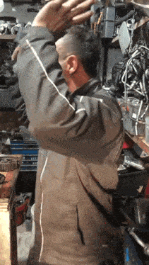a man wearing a brown jacket is standing in a garage with his arms outstretched