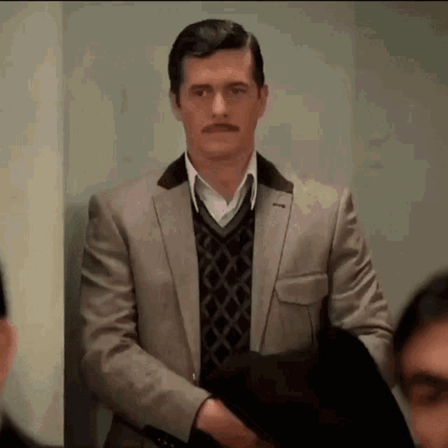 a man with a mustache is wearing a suit
