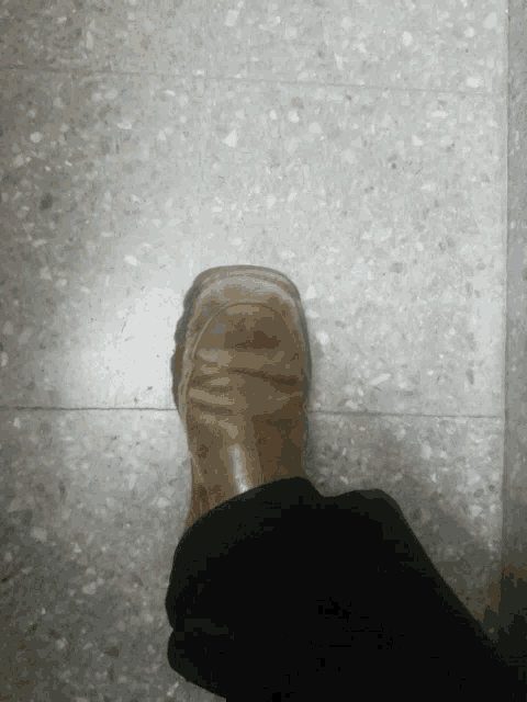 a person 's foot is standing on a tile floor