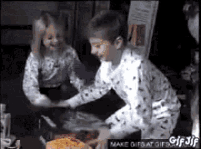 a boy and a girl are playing with a piece of food .