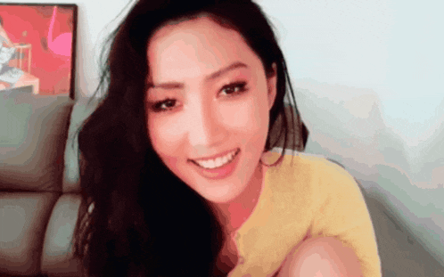 a close up of a woman 's face with a yellow shirt on