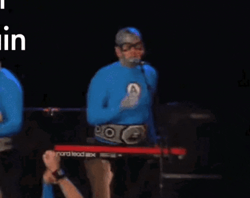 a man in a superhero costume is playing a keyboard on a stage .