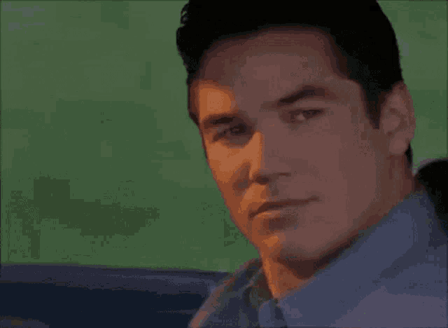 a man in a blue shirt and tie is smiling while sitting in a car .