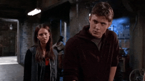a man and a woman are standing in a hallway and the man is pointing at the woman