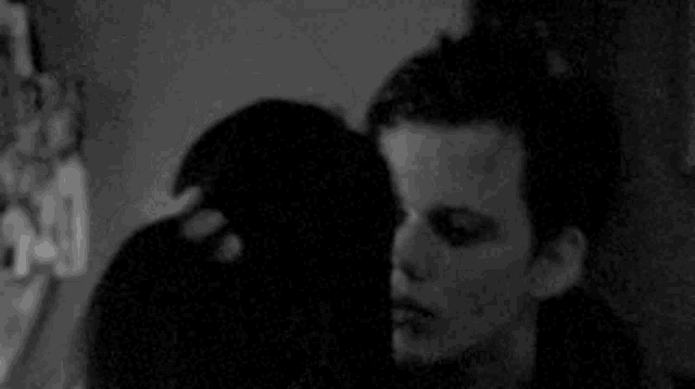 a man and woman are kissing in a black and white photo .