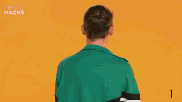 a young man in a green jacket is making a peace sign with his tongue out .