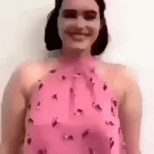 a woman wearing sunglasses and a pink dress is smiling .
