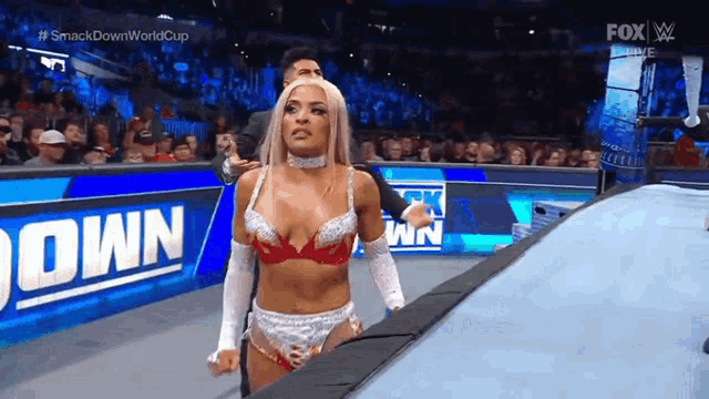 a woman in a bra and gloves is walking down the ring during a wrestling match .
