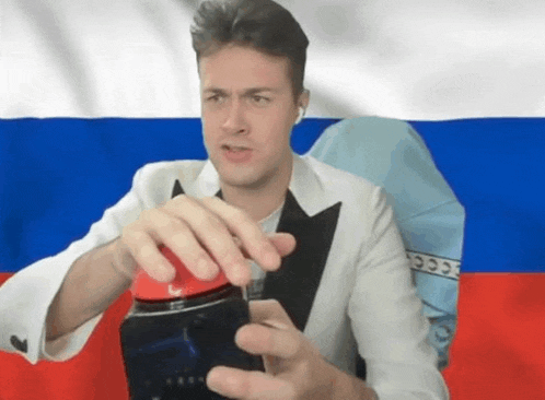 a man in a tuxedo is holding a red object in front of a russian flag ..