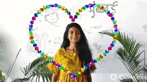 a woman in a yellow dress is standing in front of a white board with drawings on it and a heart made of flowers