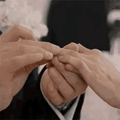 a bride and groom are putting a wedding ring on each other 's fingers .