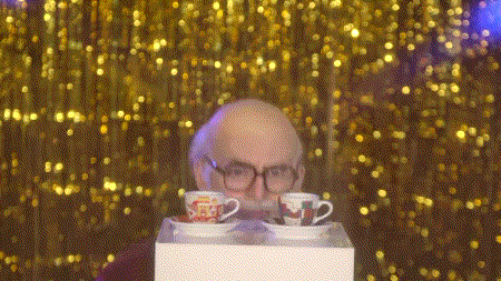 a man with glasses and a beard is looking at two cups on a box