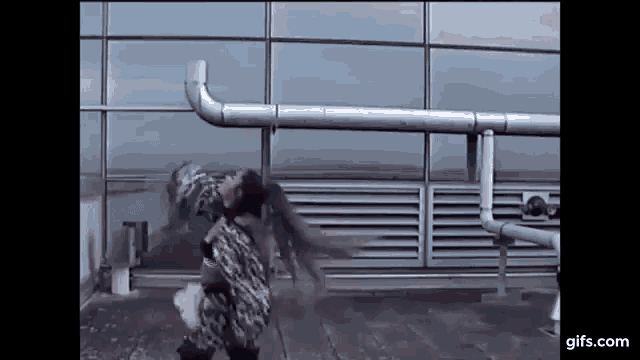 a woman is dancing on the roof of a building in front of a window .