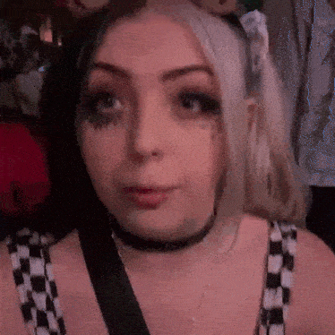 a close up of a woman 's face wearing a choker and a headband .