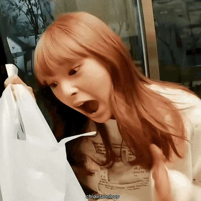 a woman with red hair is holding a white bag with her mouth open and the words chiquitaoneep below her