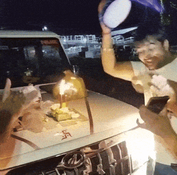 a man celebrates a birthday in front of a car with a swastika on it