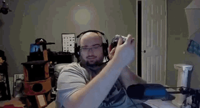 a man wearing headphones and glasses is holding a video game controller