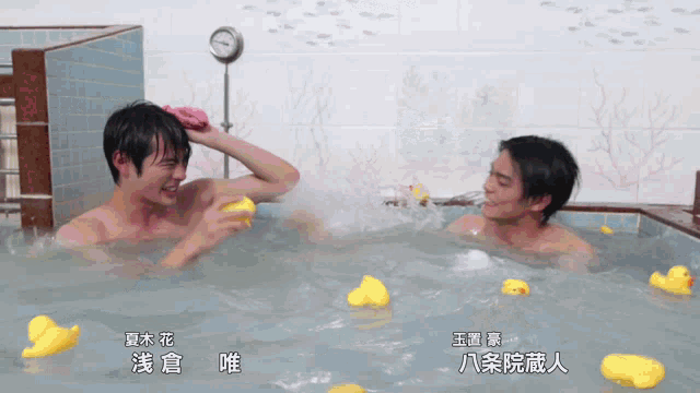 two men are taking a bath in a bathtub with rubber ducks in it