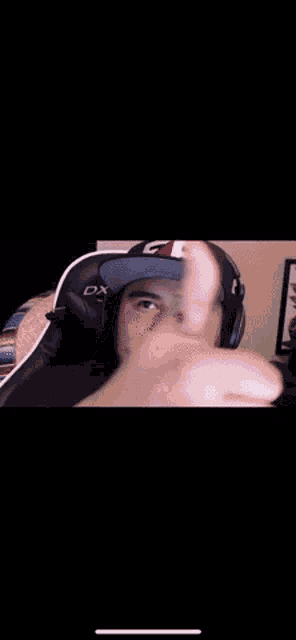 a man wearing a hat and headphones is giving a middle finger .