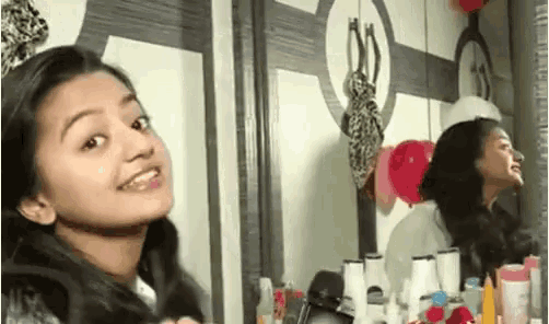 a young girl is smiling in front of a mirror while looking at herself .