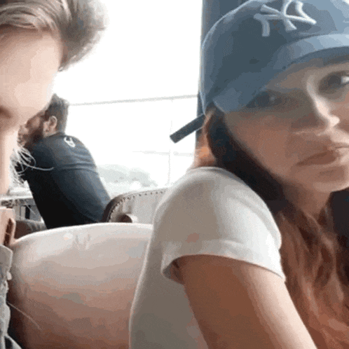 a woman wearing a new york yankees hat is sitting next to a man